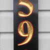 Custom sign with pineapple, gold numbers on a black background.